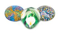 Peter Raos, (American), three glass paperweights, each with floral decoration