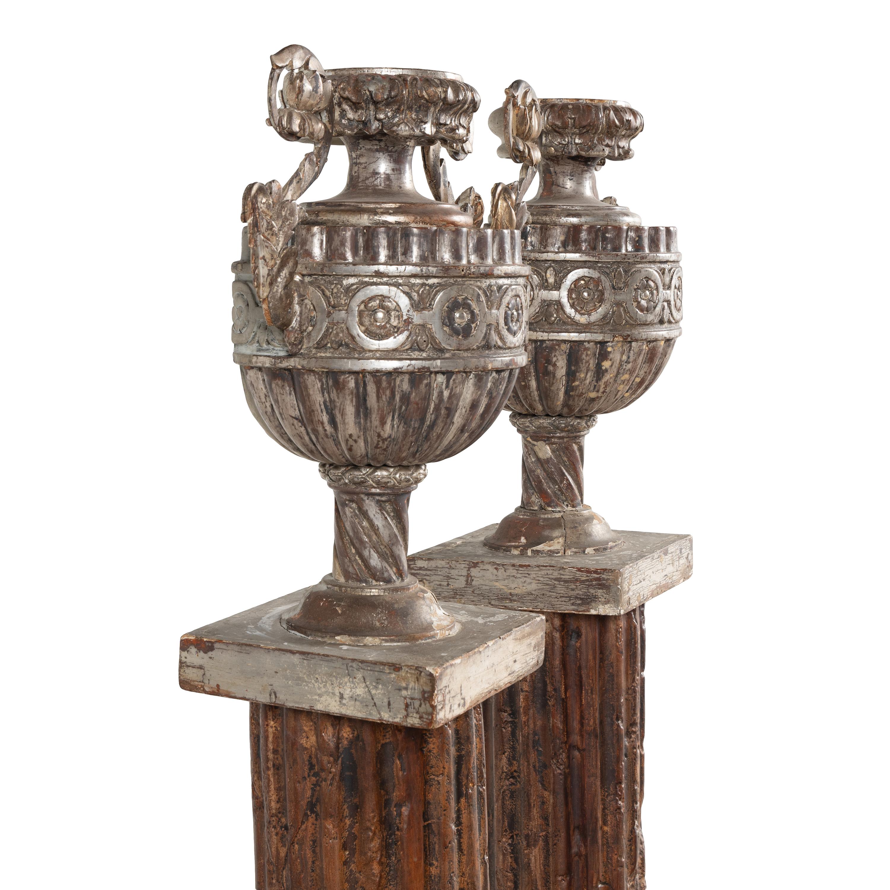 A Pair of Silvered Wood Urn-Form Finials on Painted Columnar Pedestals